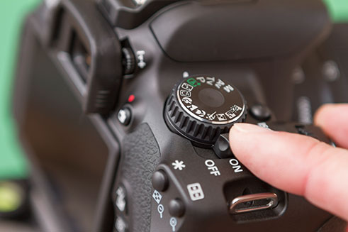 A close-up image of a dial on a digital camera, used in a camera guide. 