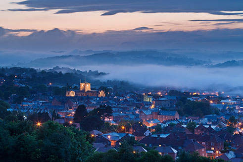 A romantic photograph of Hexham, Northumberland, at dusk, with its Abbey floodlit. 