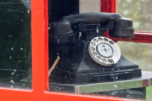 An old-fashioned telephone in a red telephone box in historic Tyneham village in Dorset. 