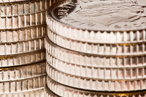 A macro shot of two piles of shiny British five pence pieces. 