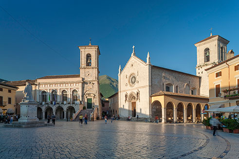 A travel image of the town of Norcia, in Perugia, Italy, lit by bright sunshine. 